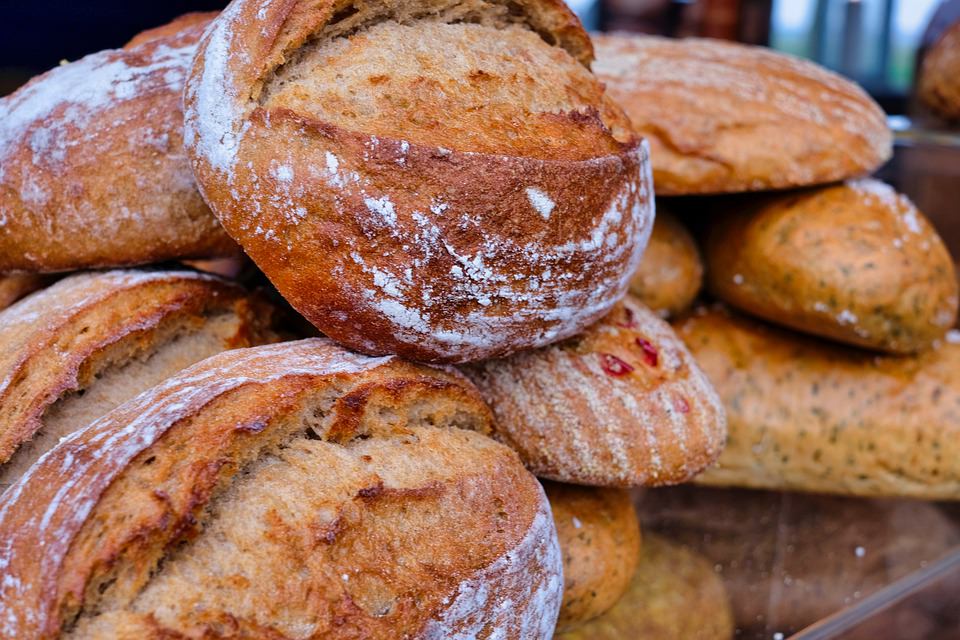 Stacks of fresh baked bread, goldened brown and dusted with flour.
