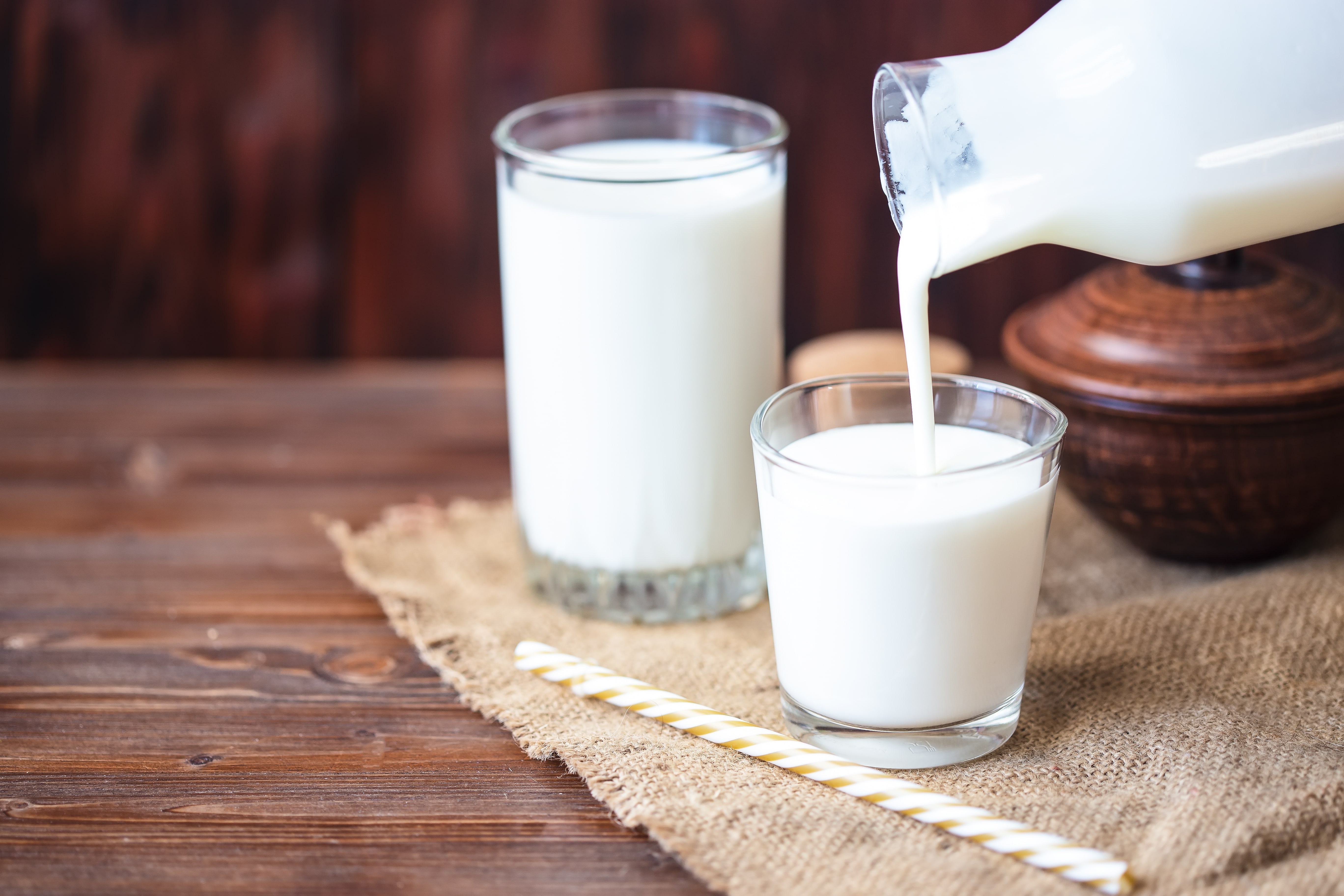 Pouring homemade butermilk with probiotics on woden table.