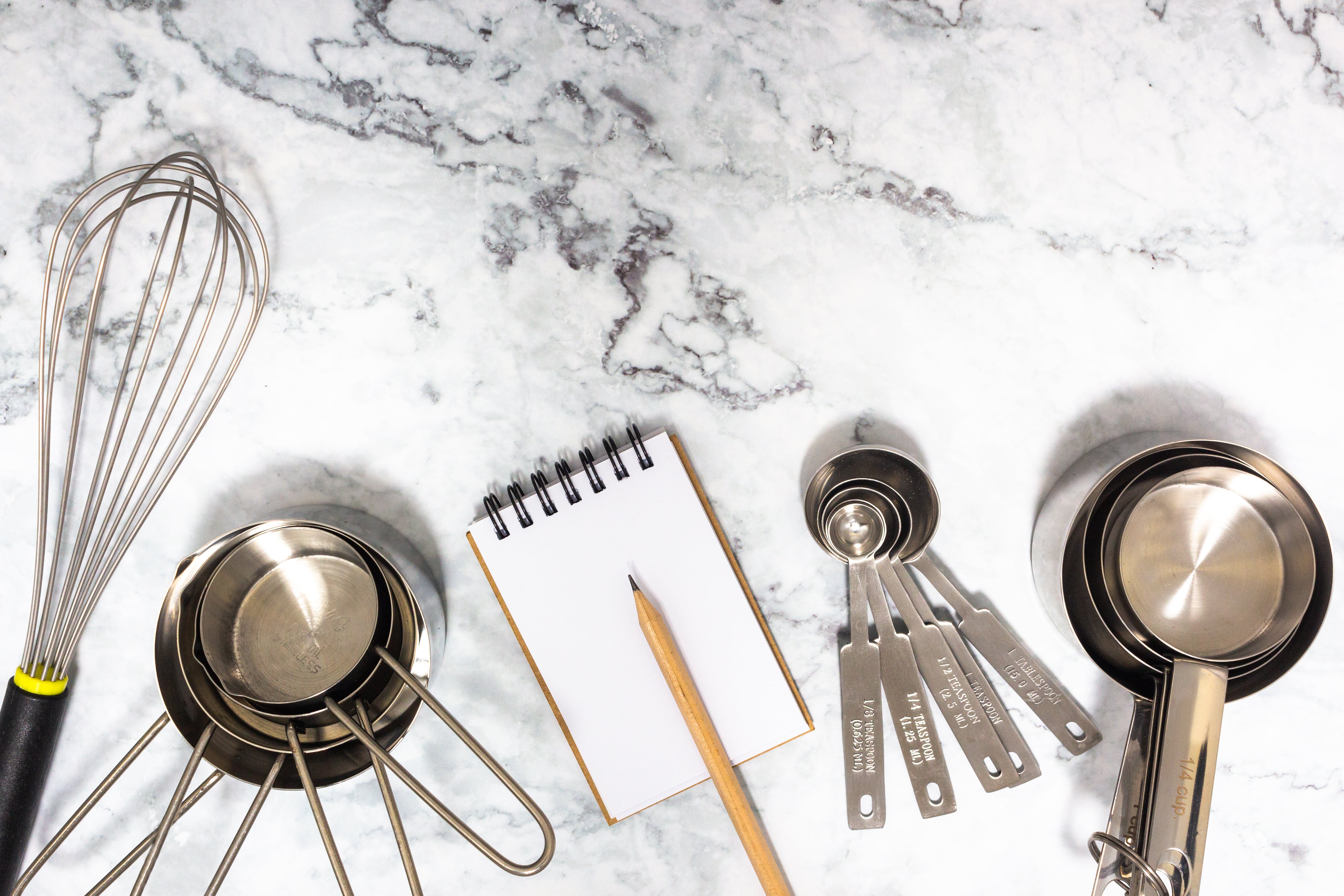 Measuring ingredients by follow recipe with measuring cups, measuring spoons and beat with whisk on marble tabletop.