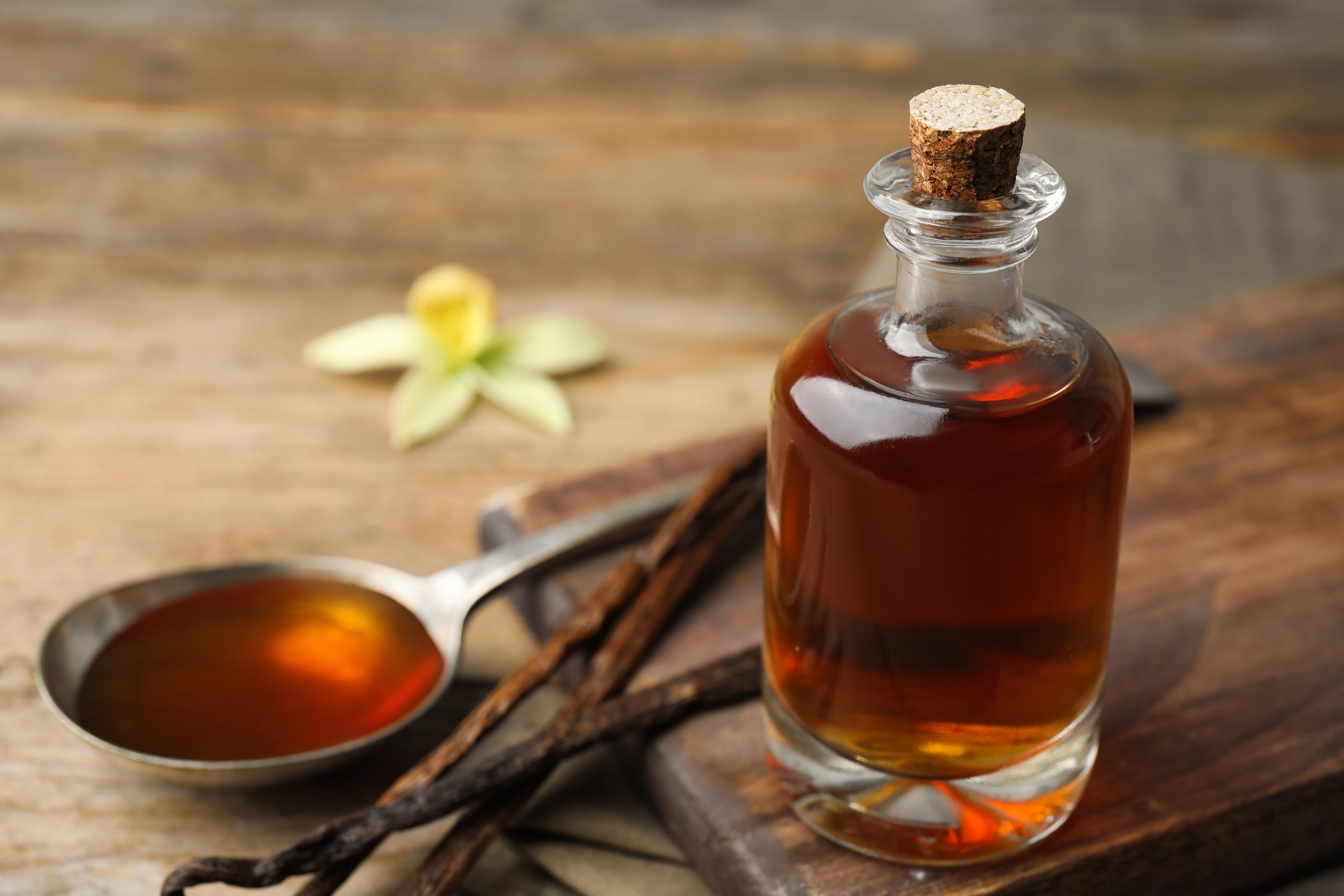 Aromatic homemade vanilla extract on wooden table.