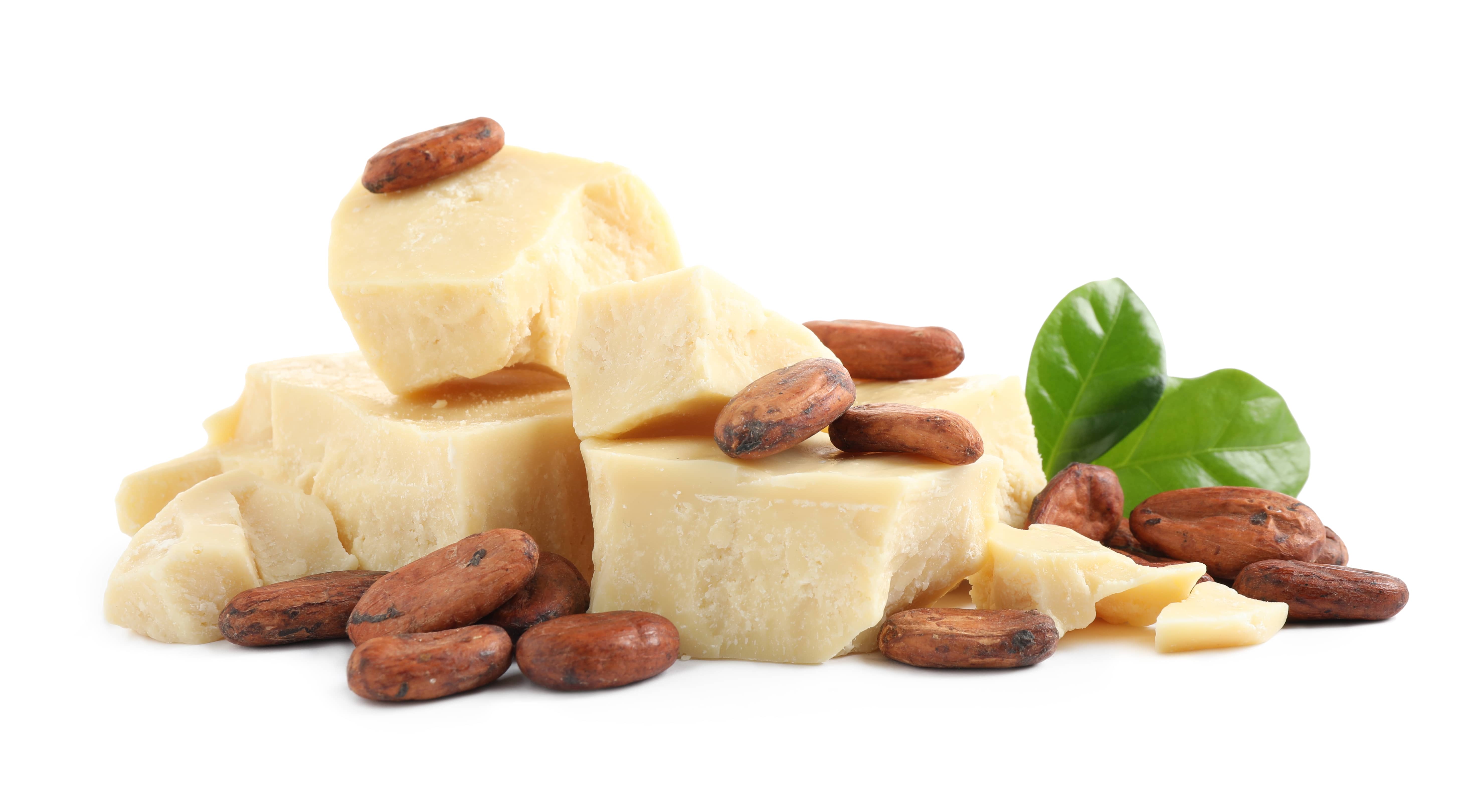 Cocoa butter, beans and green leaves isolated on white background.