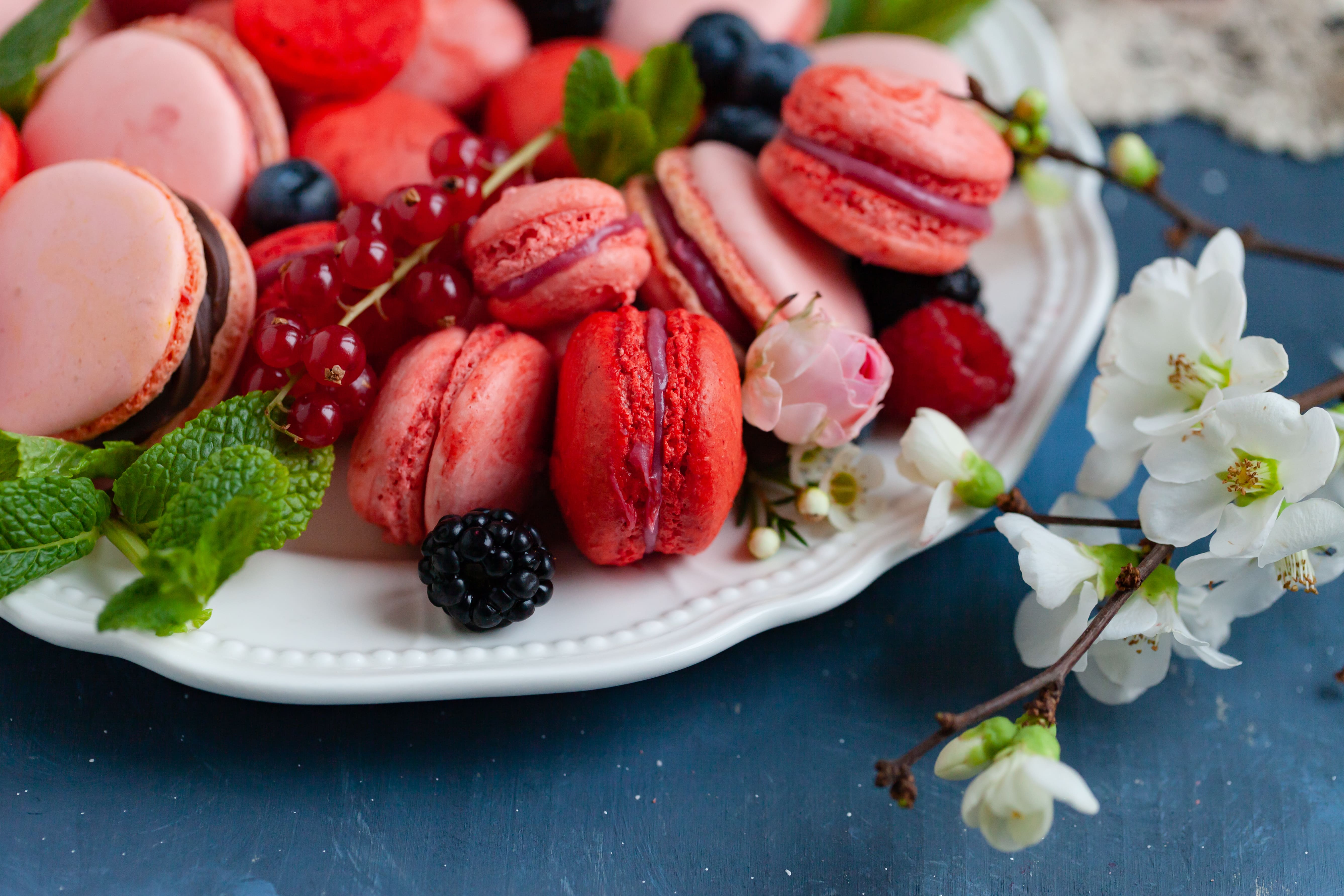 Colorful and bright macarons. Natural fruit and berry flavors, sweet creamy stuffing. Top view. Dark blue background.