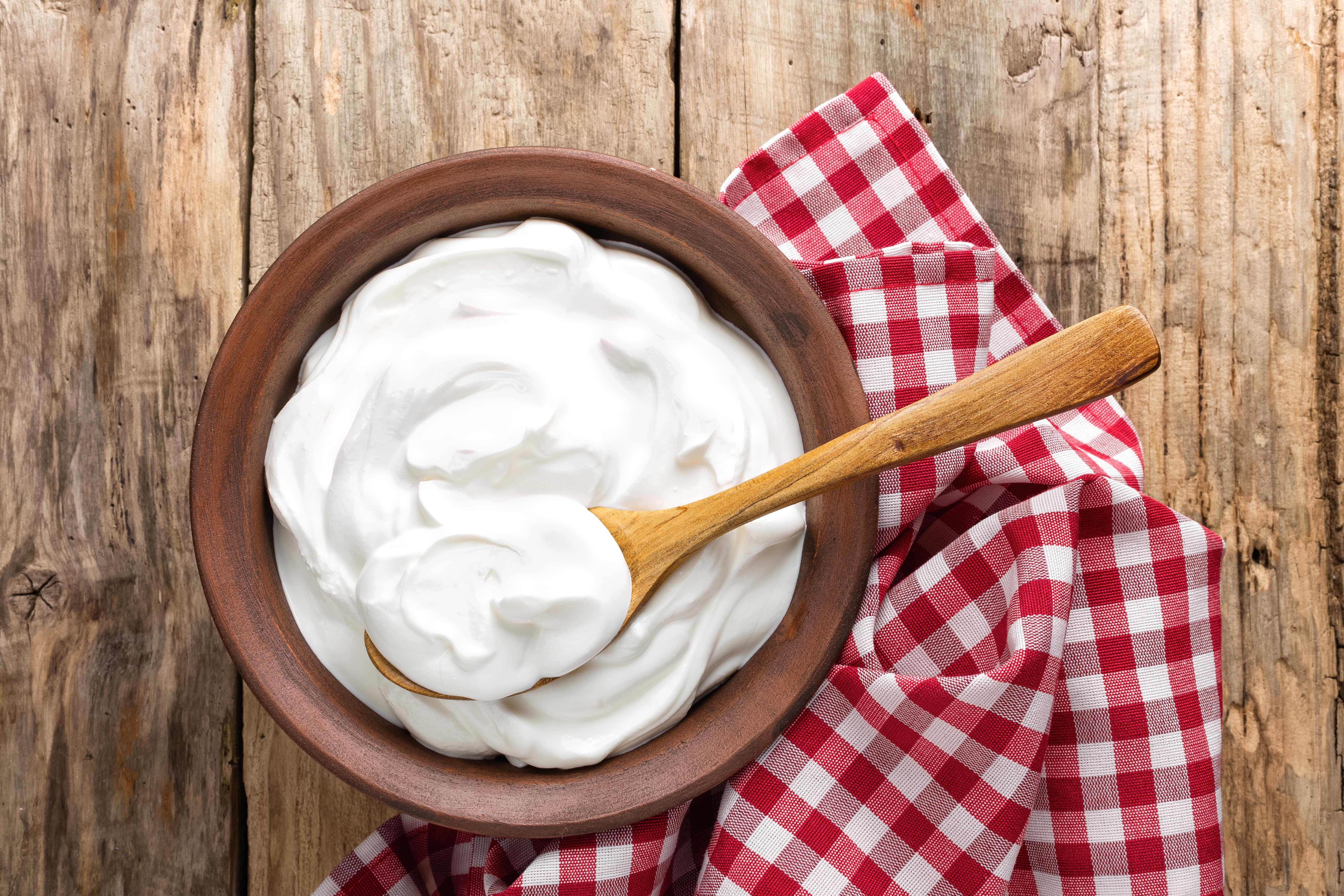 Crème Fraîche in wooden bowl with the spoon on the woden table