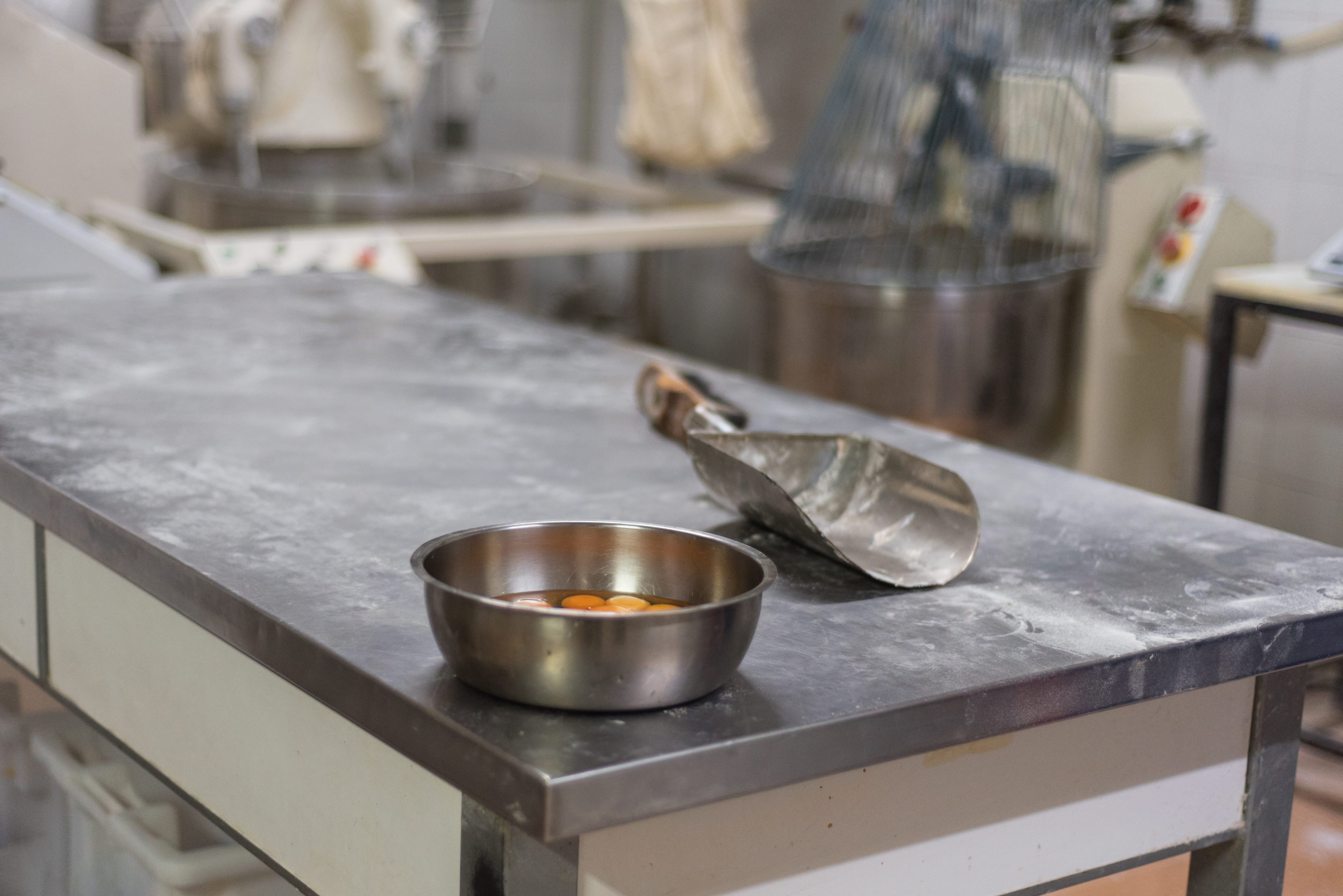Bowl with ingredients and utensils in industrial bakery.