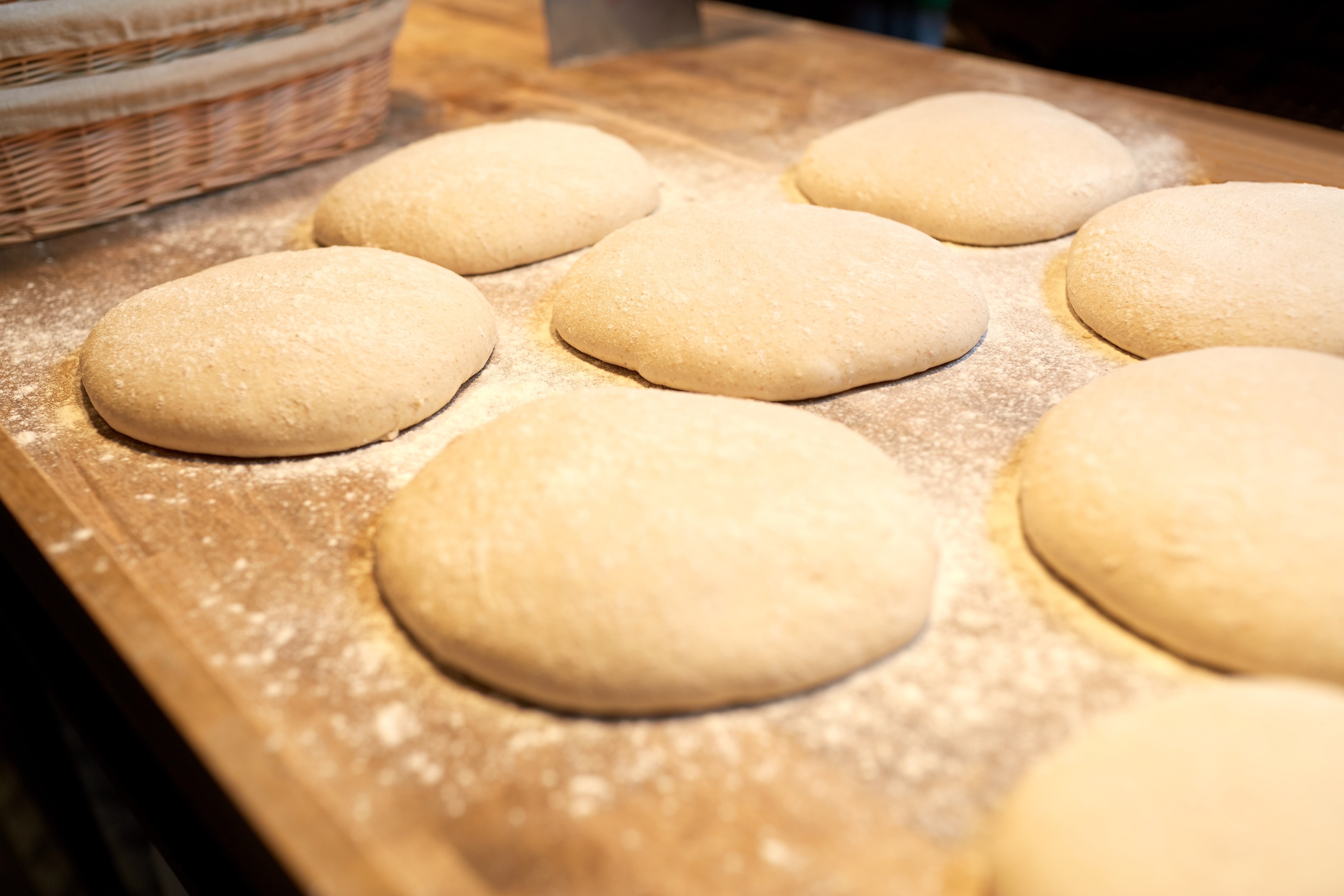 Yeast bread dough rising on wooden kitchen table at bakery.