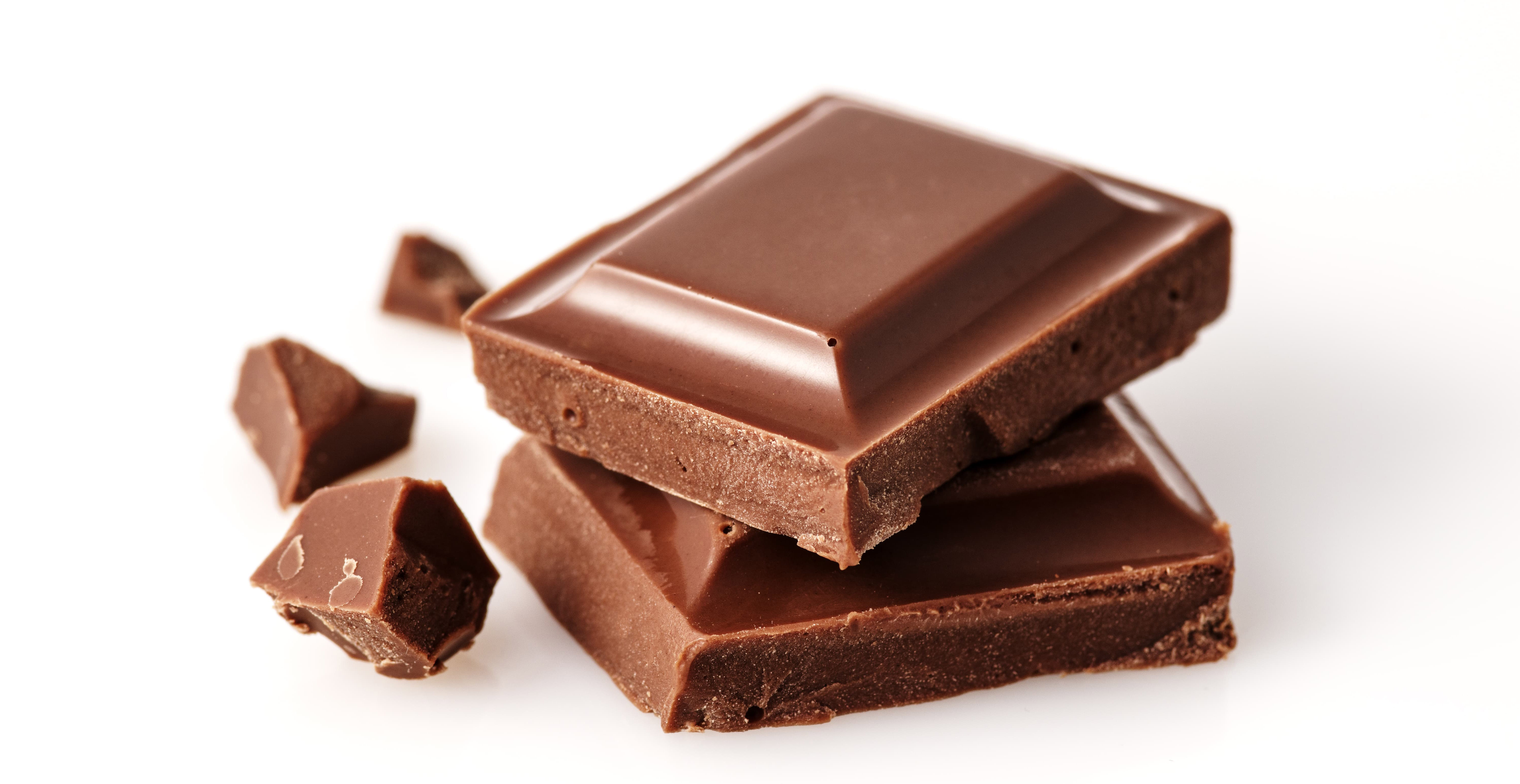 Broken pieces of milk chocolate bar over white background.