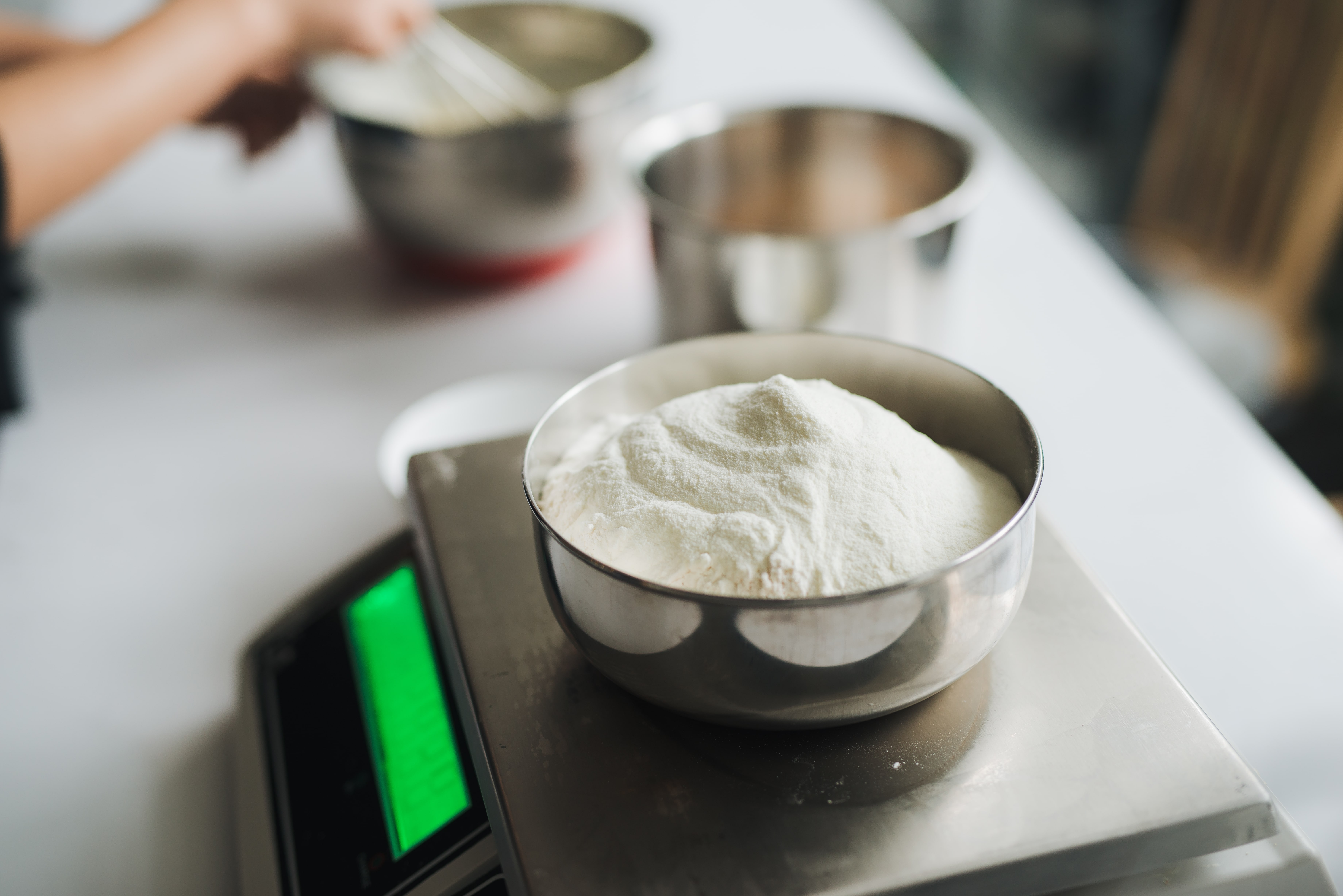 Bakery chef weighing flour on the digital scale.