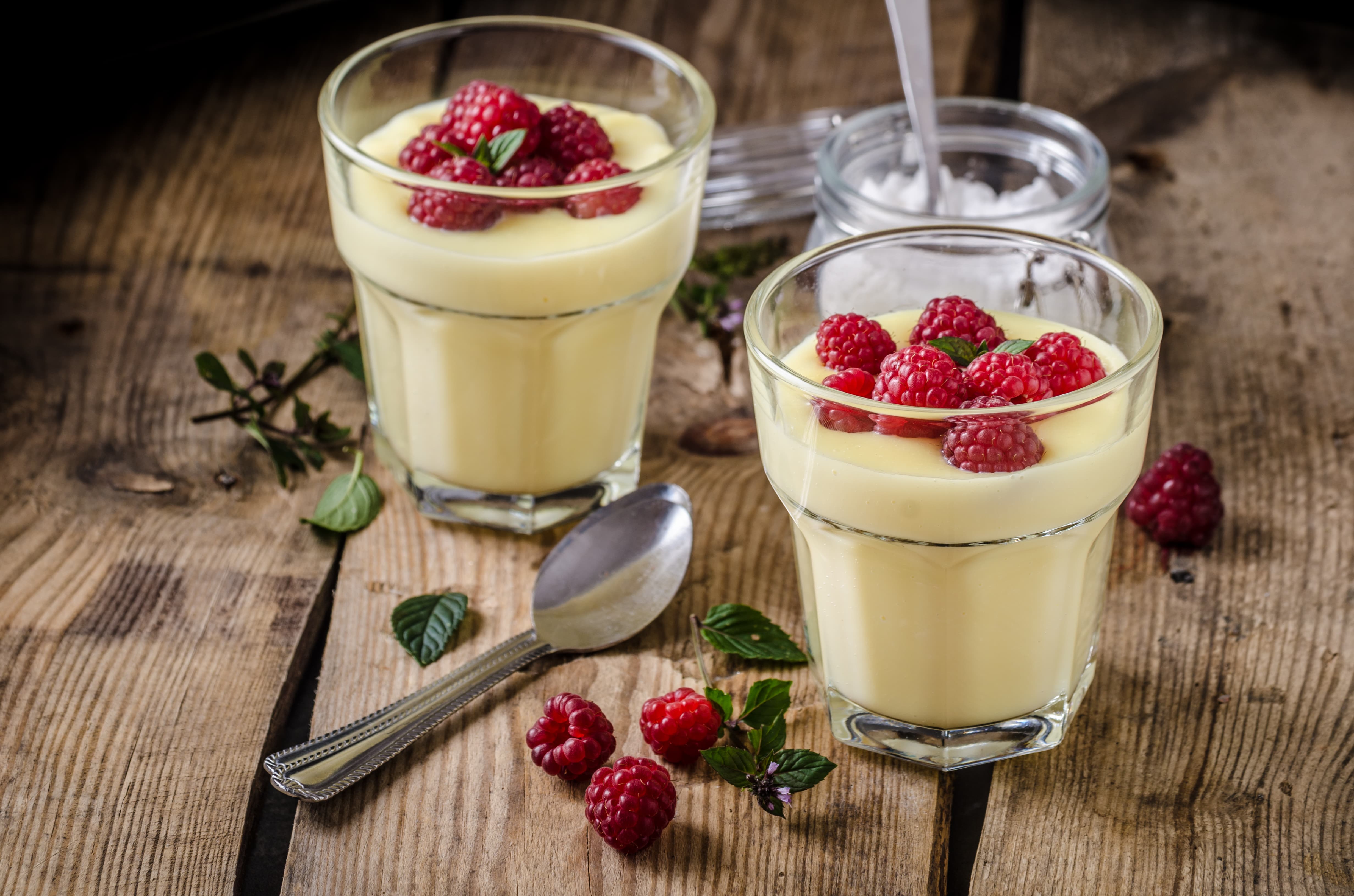 Vanilla berries pudding served in the glasses with raspberries on the top.